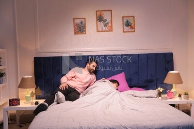 a father sitting on the bed during his boy&#39;s sleep