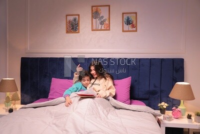 a woman reading a story to her son in bed