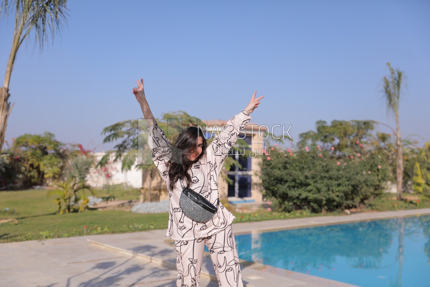 a woman standing in the garden beside a swimming pool