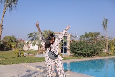 a woman standing in the garden beside a swimming pool
