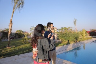 a husband with his wife standing in front of a swimming pool