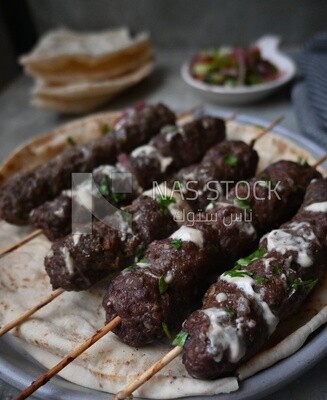 Dish with grilled kofta with tahini sauce on it