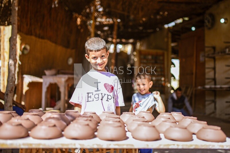 Two boys in front of a table with pottery products