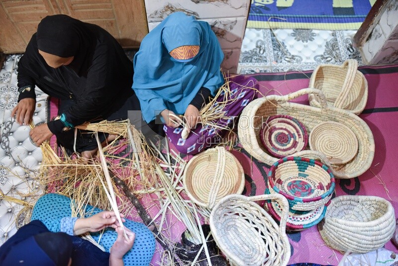 Women shaping wicker into cages and baskets