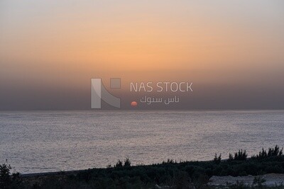 Sunset behind the horizon line on the sea