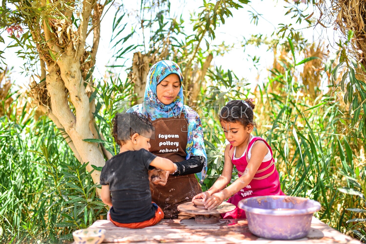 Woman from Upper Egypt teaching children to make pottery