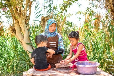 Woman from Upper Egypt teaching children to make pottery