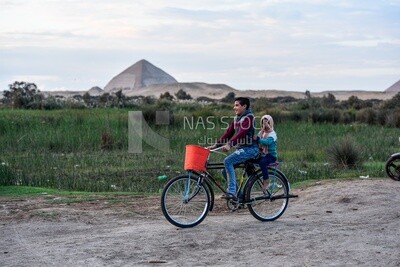 Boy rides a bike and his sister sits behind him