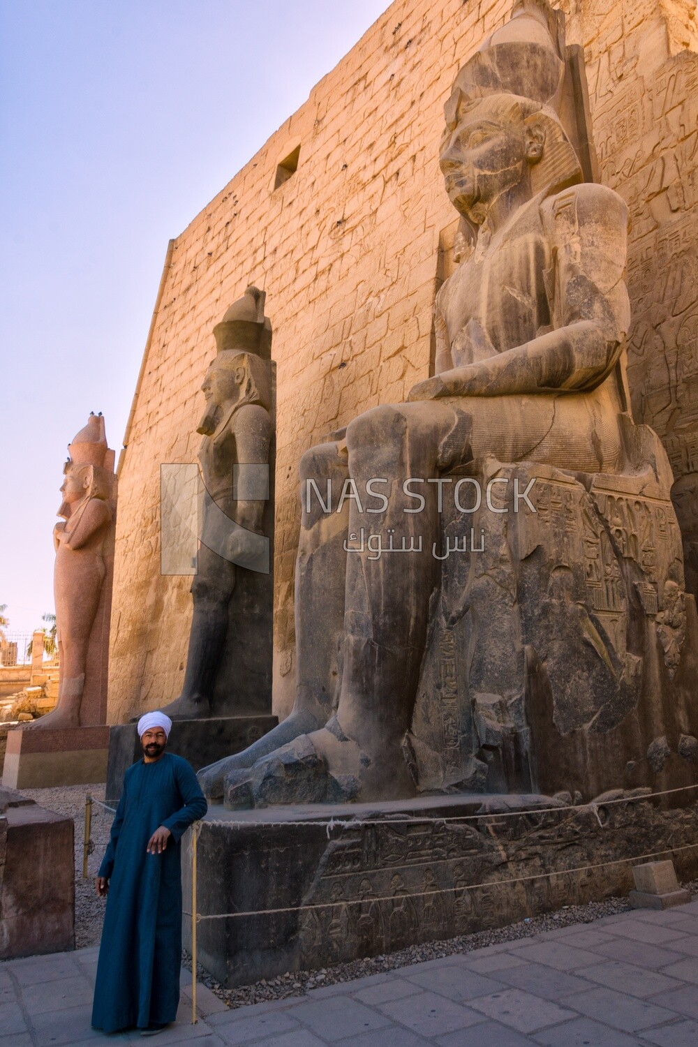 Man standing next to a statue at a temple, famous landmarks, museum