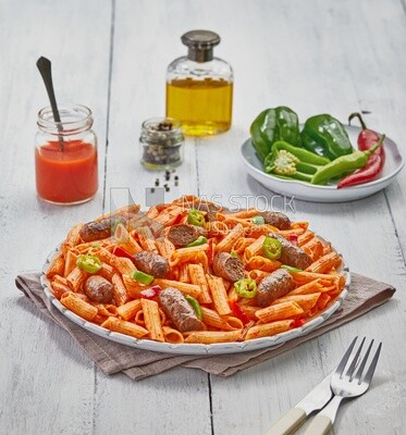 Side view of a plate of pasta with sausage and appetizers