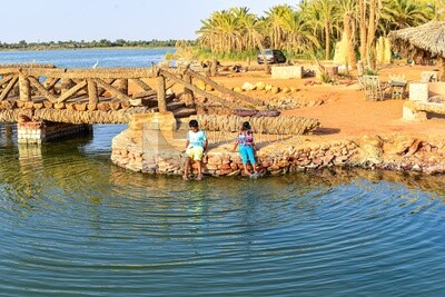 Children sit on the shore of Fatnas Lake in Siwa Oasis