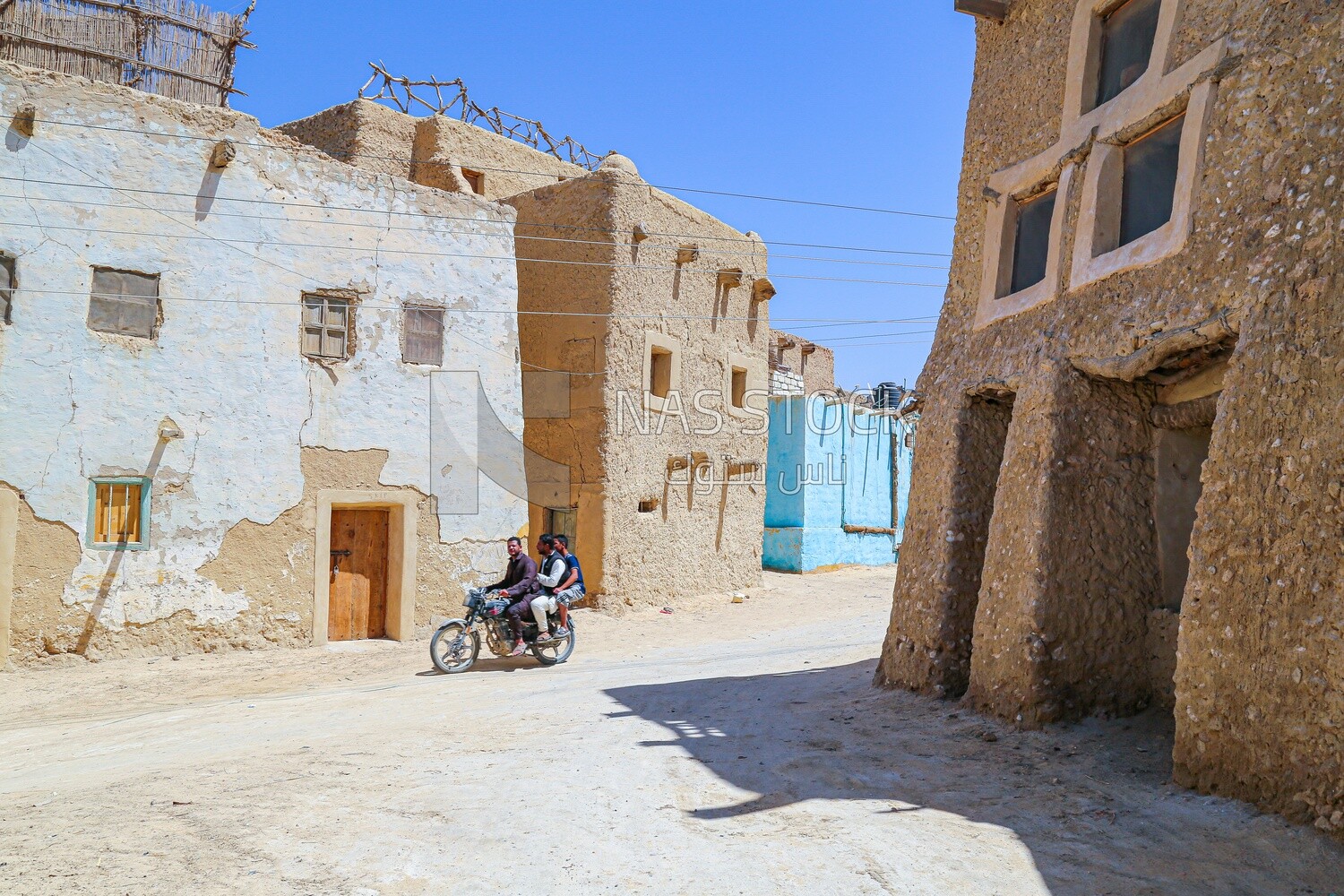 People riding a motorcycle going through the streets of Siwa Oasis