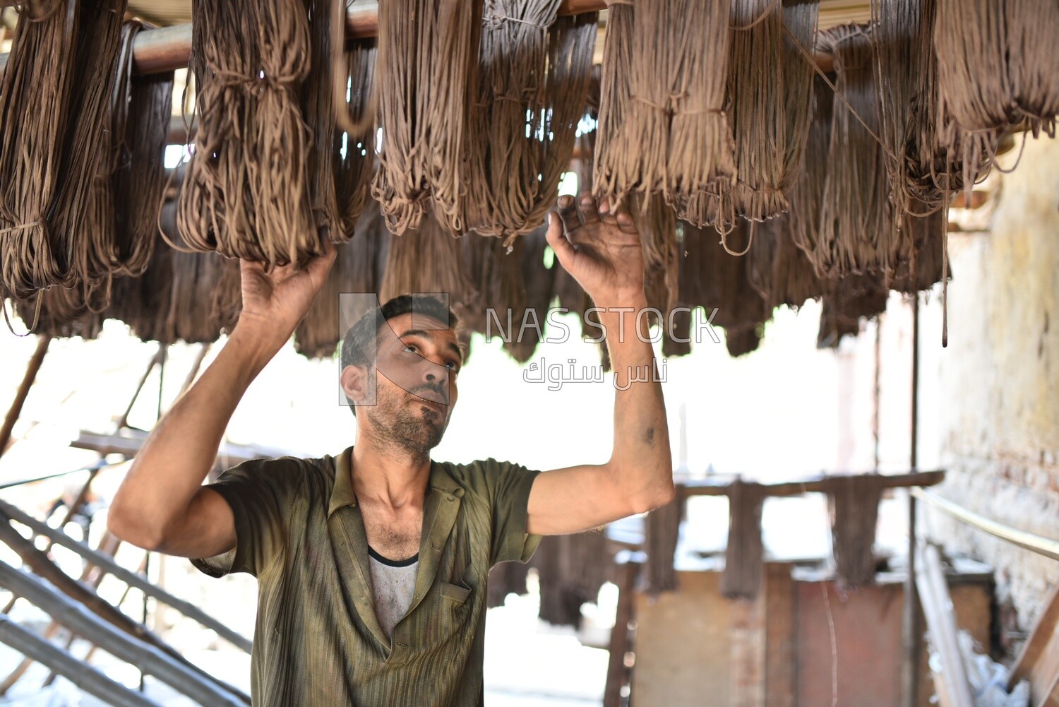 A worker hangs the brown threads