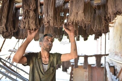 عامل يقوم بتعليق الخيوط البنية