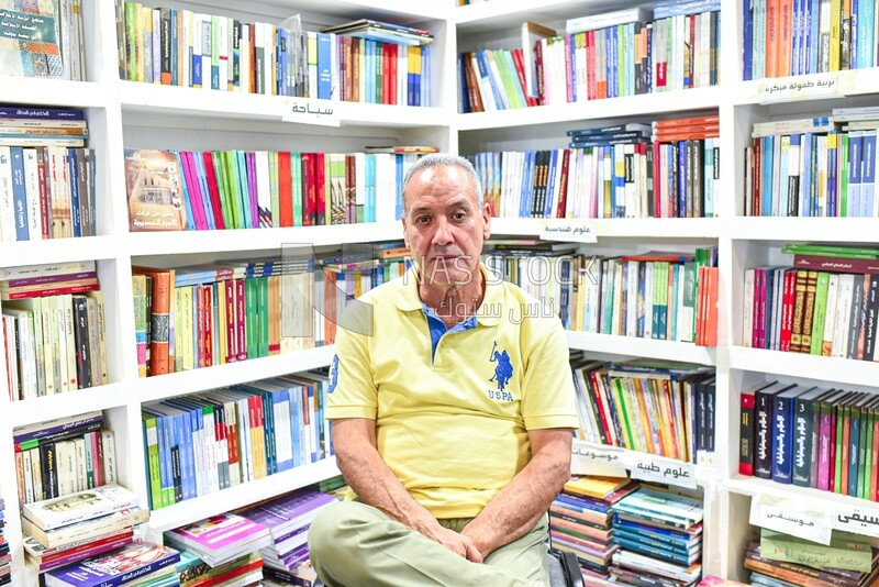 A scene of a man sitting in his book booth at a book fair
