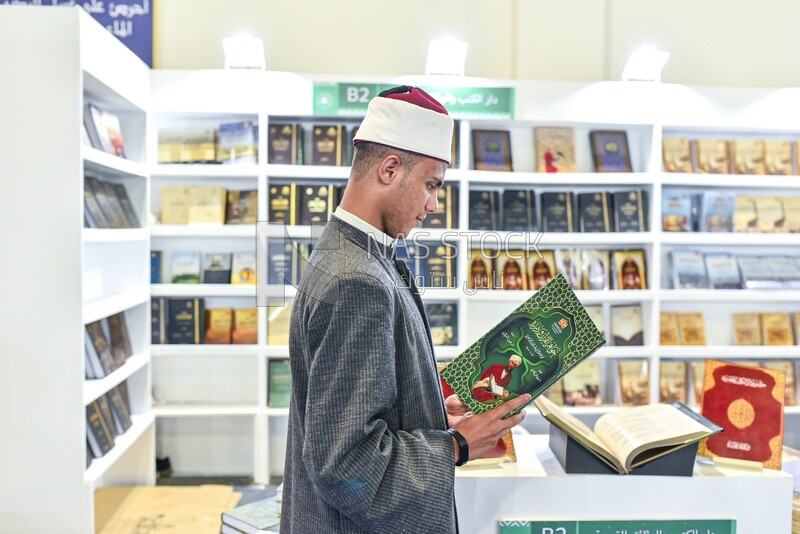 An imam browsing a book at a book fair