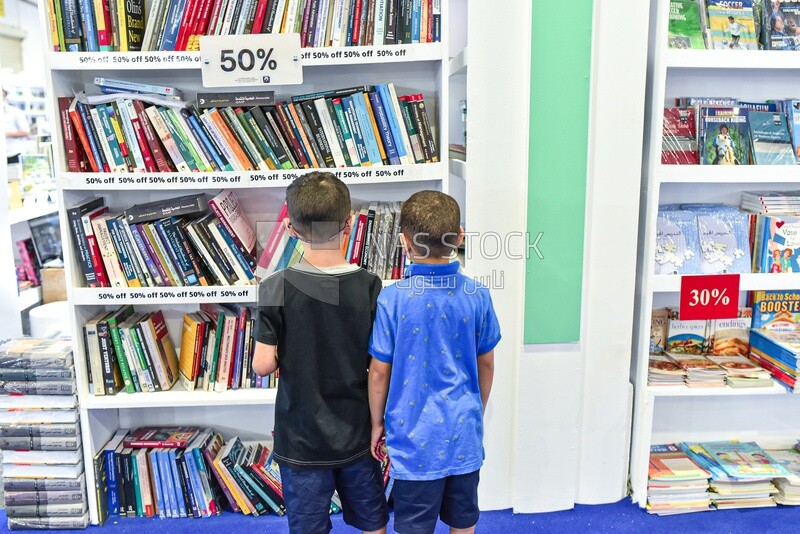 اطفال يبحثون فى كتب الاطفال عن قصة مسلية فى معرض الكتاب
