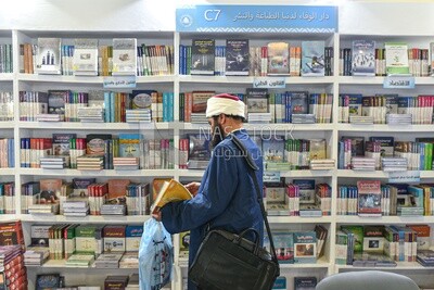 An imam browsing a book at a book fair