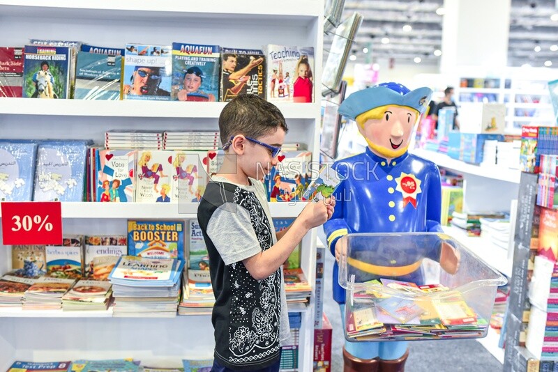 Child looking in children's books for an entertaining story at the book fair