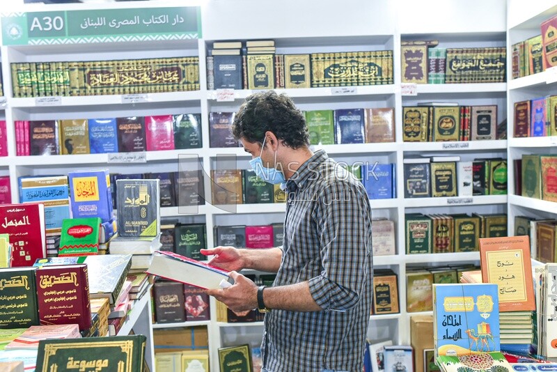 The scene of a person buying a book from a publishing house for religious books and references at a book fair