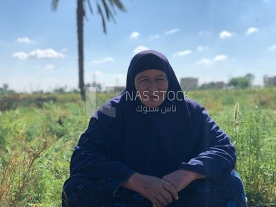 An Egyptian woman sits in the field among the plants