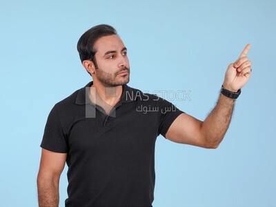 Photo Of a Handsome man Standing and pointing away, Smiling Man, Wearing Casual Clothes Posing In a Light Room Interior, Smiling At the Camera