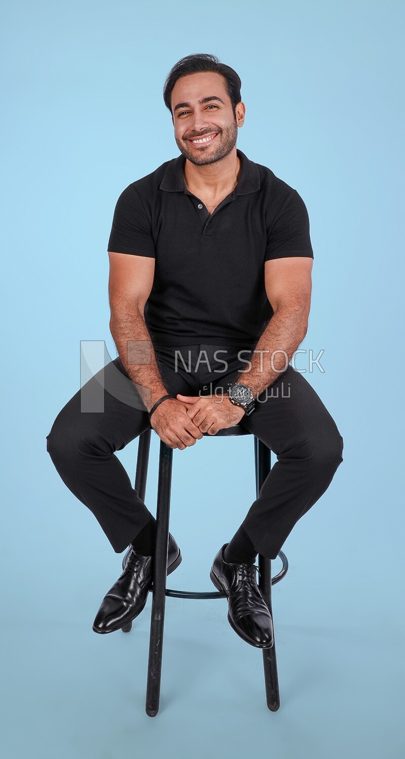 Photo Of a Handsome man sitting on the chair, Smiling Man, Wearing Casual Clothes Posing In a Light Room Interior, Smiling At the Camera