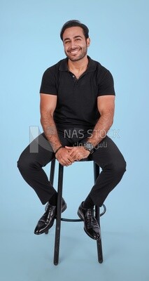 Photo Of a Handsome man sitting on the chair, Smiling Man, Wearing Casual Clothes Posing In a Light Room Interior, Smiling At the Camera