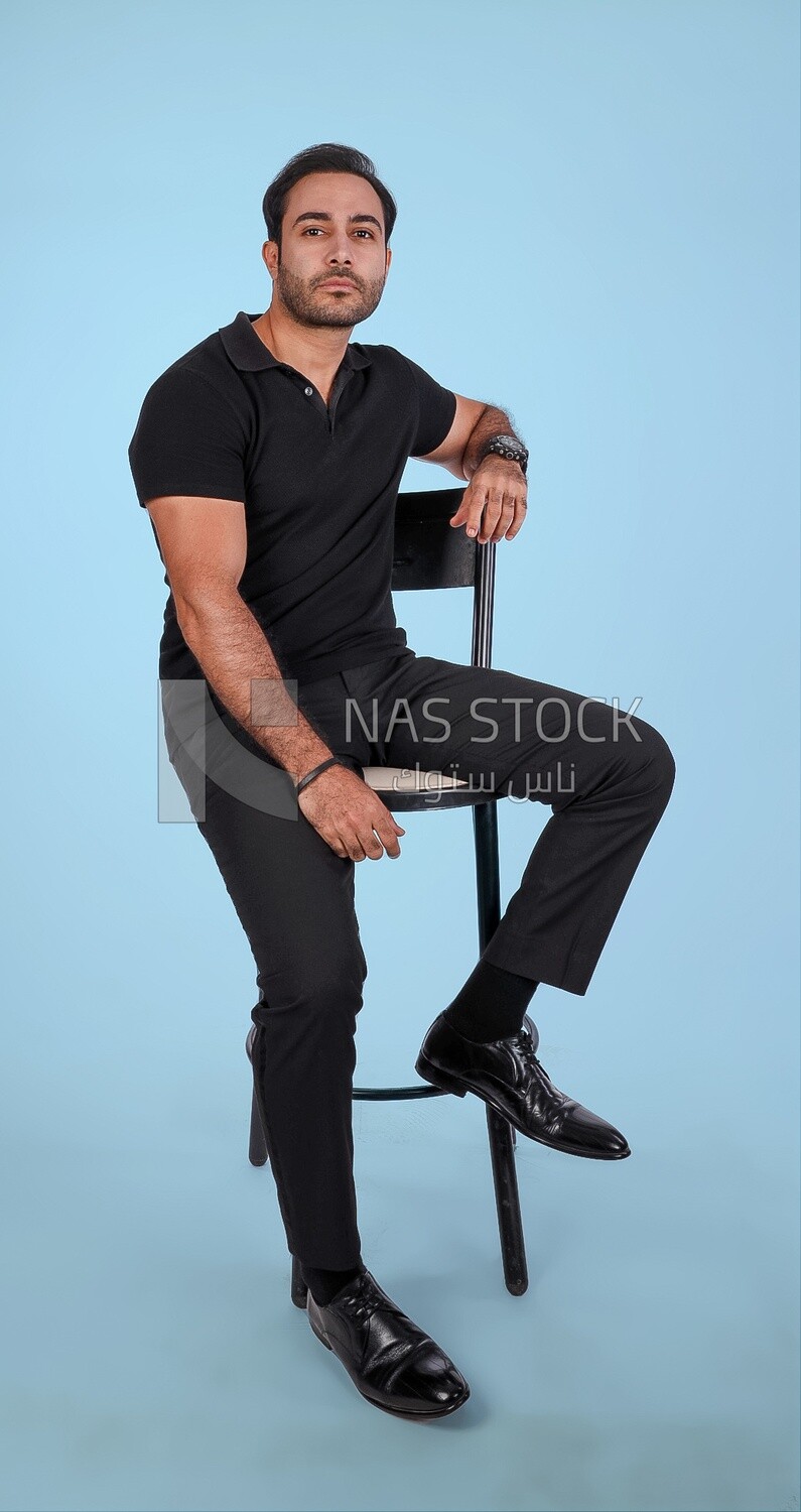 Photo Of a Handsome man sitting on the chair, Smiling Man, Wearing Casual Clothes Posing In a Light Room Interior, Smiling At the Camera