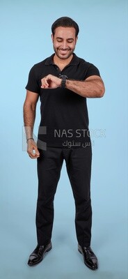Portrait Of a Handsome man Standing and looking at his watch, Smiling Man, Wearing Casual Clothes Posing In a Light Room Interior, Smiling At the Camera
