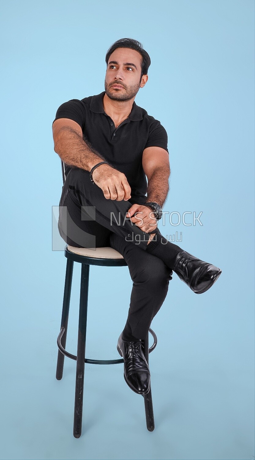 Photo of a Handsome man sitting on a chair and putting a leg on a leg, Smiling Man, Wearing Casual Clothes Posing In a Light Room Interior, Smiling At the Camera