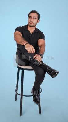 Photo of a Handsome man sitting on a chair and putting a leg on a leg, Smiling Man, Wearing Casual Clothes Posing In a Light Room Interior, Smiling At the Camera