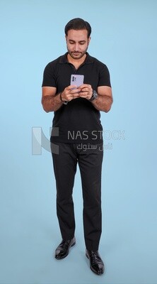 Photo Of a Handsome man Standing and holding his mobile, Smiling Man, Wearing Casual Clothes Posing In a Light Room Interior, Smiling At the Camera