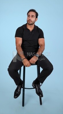 Photo Of a Handsome man sitting on the chair, Smiling Man, Wearing Casual Clothes Posing In a Light Room Interior, Smiling At the Camera