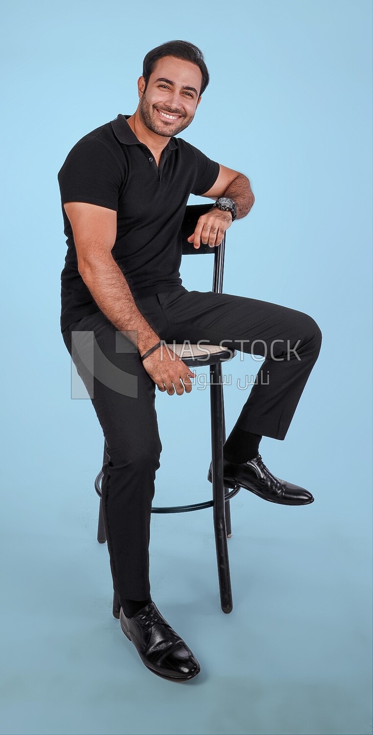 Photo Of a Handsome man sitting on the chair, Smiling Man, Wearing Casual Clothes Posing In a Light Room Interior, Smiling At the Camera