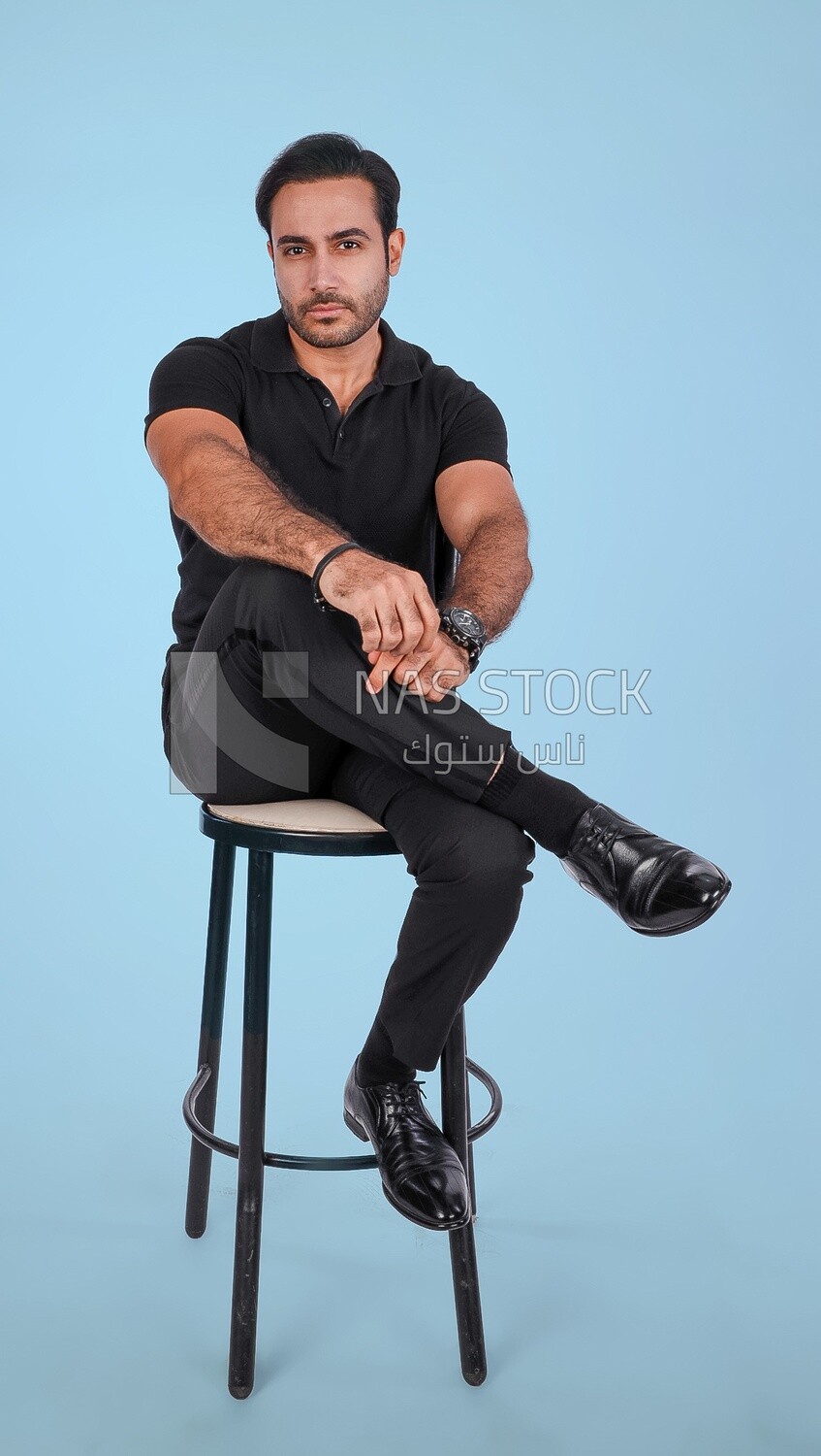 Photo of a Handsome man sitting on a chair and putting a leg on a leg, Smiling Man, Wearing Casual Clothes Posing In a Light Room Interior, Smiling At the Camera