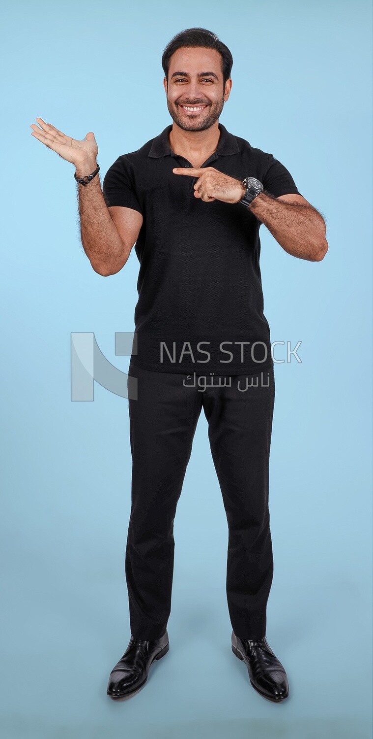 Photo Of a Handsome man Standing and pointing away, Smiling Man, Wearing Casual Clothes Posing In a Light Room Interior, Smiling At the Camera