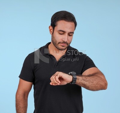 Portrait Of a Handsome man Standing and looking at his watch, Smiling Man, Wearing Casual Clothes Posing In a Light Room Interior, Smiling At the Camera