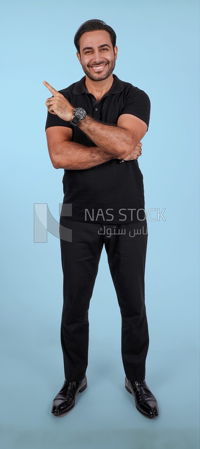 Photo Of a Handsome man Standing and pointing away, Smiling Man, Wearing Casual Clothes Posing In a Light Room Interior, Smiling At the Camera