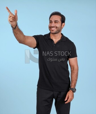 Photo Of a Handsome man Standing and pointing away, Smiling Man, Wearing Casual Clothes Posing In a Light Room Interior, Smiling At the Camera
