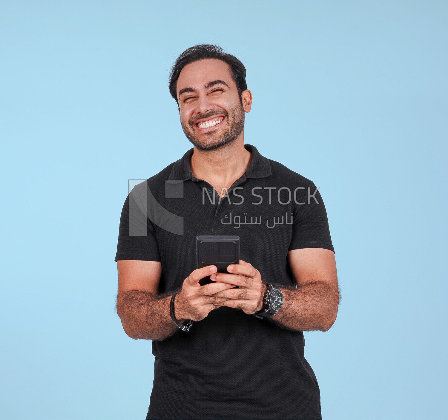 Photo Of a Handsome man Standing and holding his mobile, Smiling Man, Wearing Casual Clothes Posing In a Light Room Interior, Smiling At the Camera