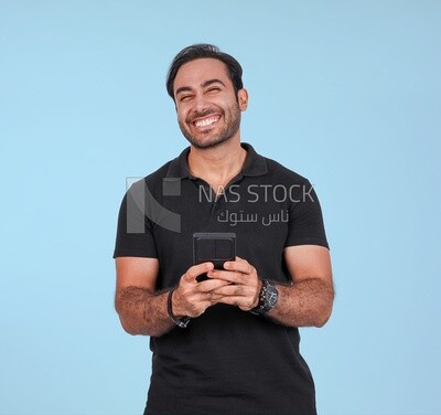 Photo Of a Handsome man Standing and holding his mobile, Smiling Man, Wearing Casual Clothes Posing In a Light Room Interior, Smiling At the Camera