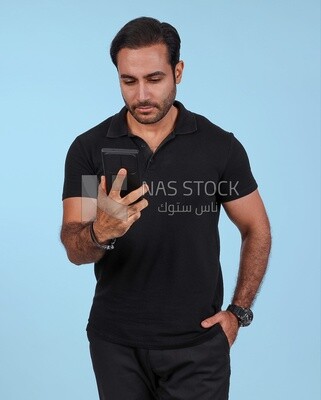 Photo Of a Handsome man Standing and holding his mobile, Smiling Man, Wearing Casual Clothes Posing In a Light Room Interior, Smiling At the Camera
