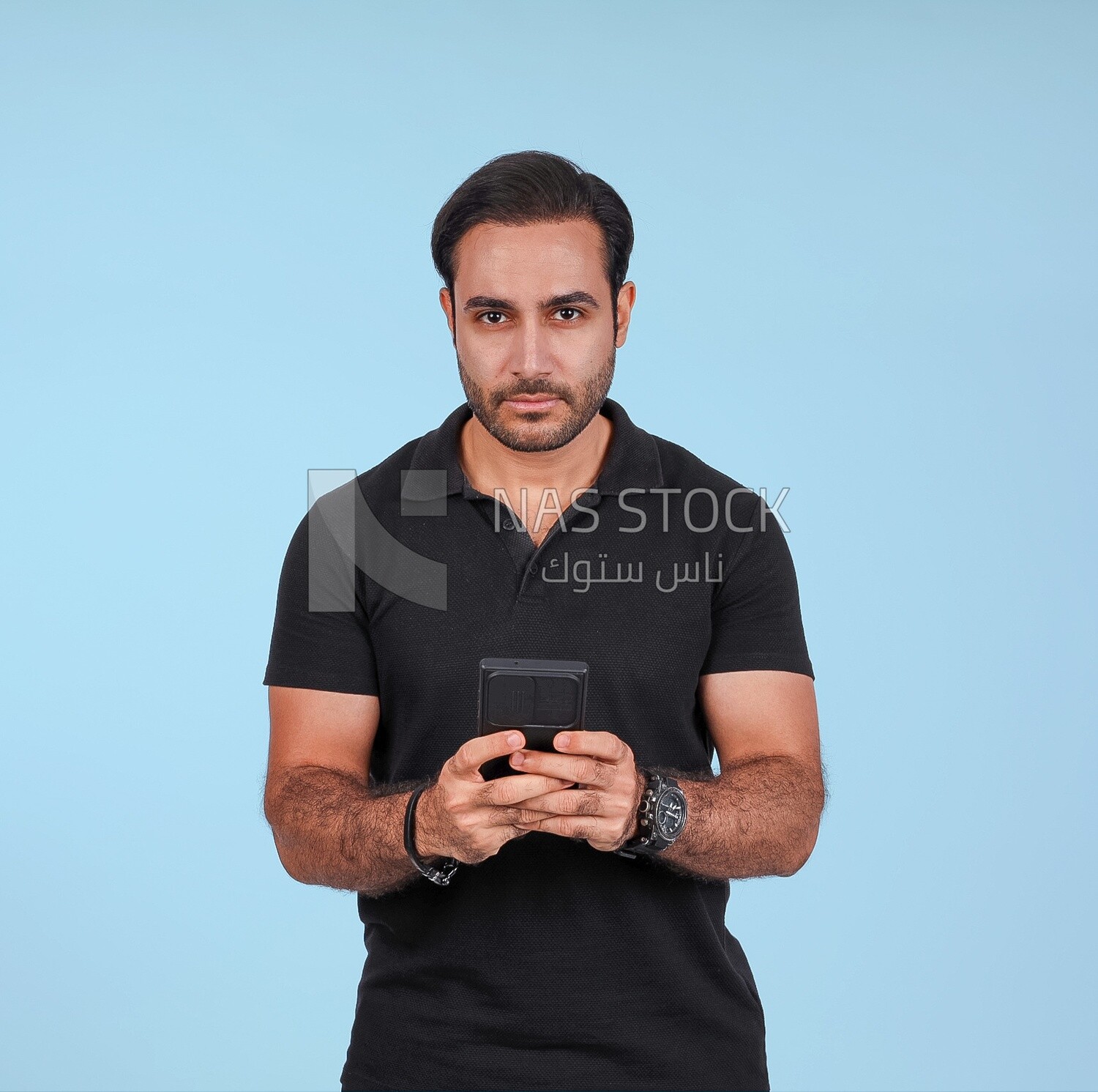 Photo Of a Handsome man Standing and holding his mobile, Smiling Man, Wearing Casual Clothes Posing In a Light Room Interior, Smiling At the Camera