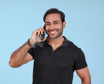 Photo Of a Handsome man Standing and talking in the mobile, Smiling Man, Wearing Casual Clothes Posing In a Light Room Interior, Smiling At the Camera