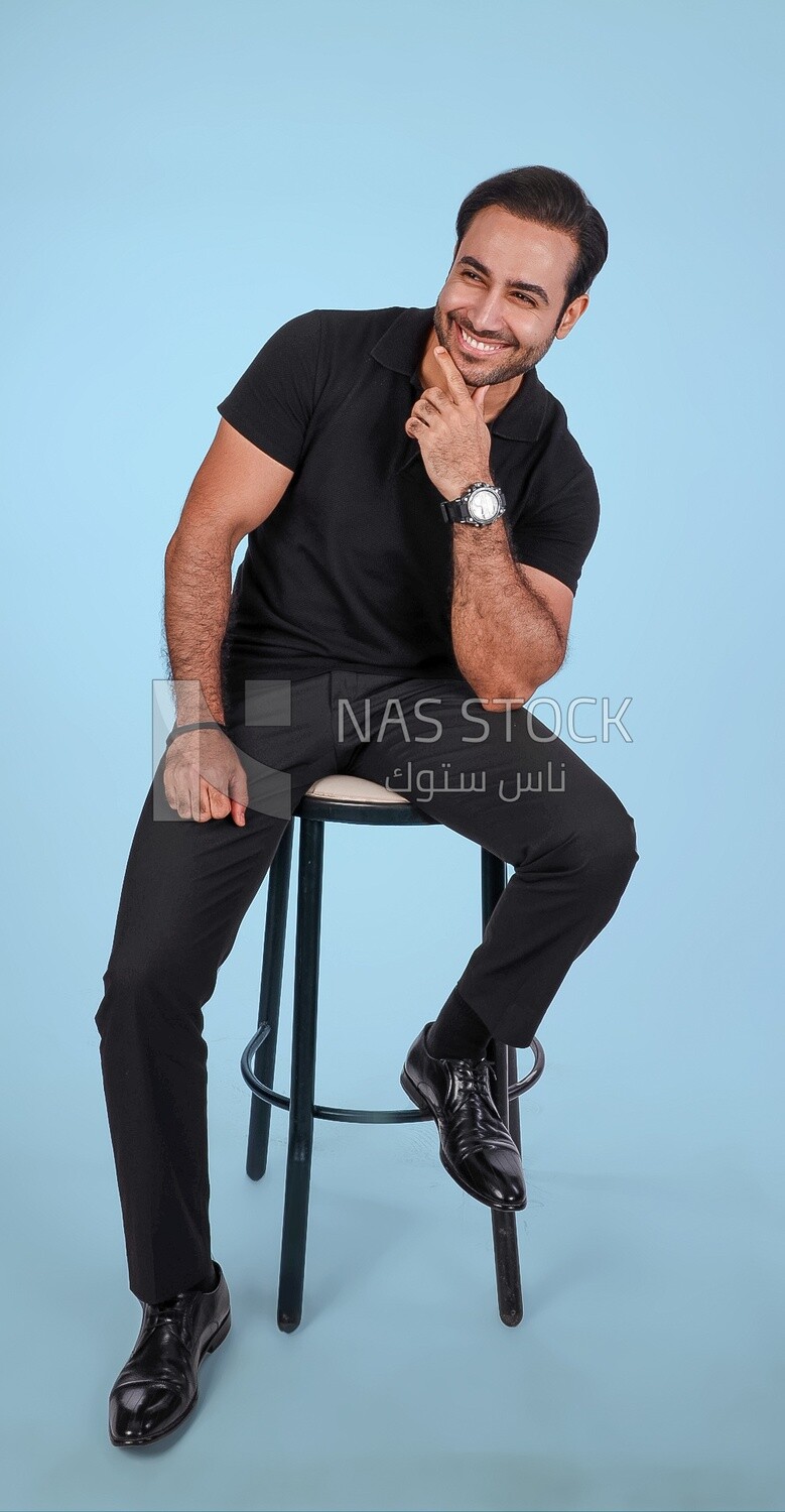 Photo Of a Handsome man sitting on the chair, Smiling Man, Wearing Casual Clothes Posing In a Light Room Interior, Smiling At the Camera