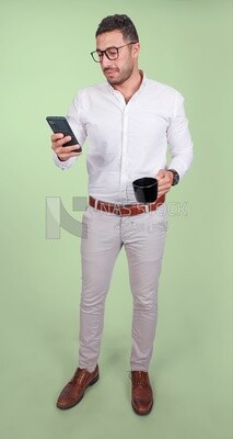 Photo of a handsome man wearing glasses standing looking at his phone and drinking coffee, business development and partnerships, business meeting, model