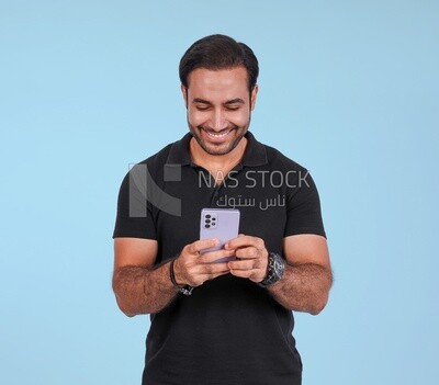 Photo Of a Handsome man Standing and holding his mobile, Smiling Man, Wearing Casual Clothes Posing In a Light Room Interior, Smiling At the Camera
