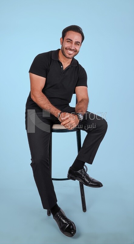 Photo Of a Handsome man sitting on the chair, Smiling Man, Wearing Casual Clothes Posing In a Light Room Interior, Smiling At the Camera