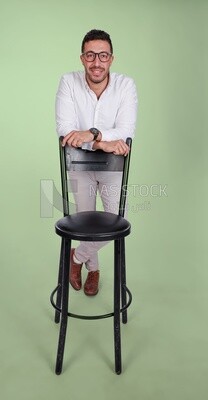 Photo of a handsome man wearing glasses standing and leaning on a chair, business development and partnerships, business meeting, model